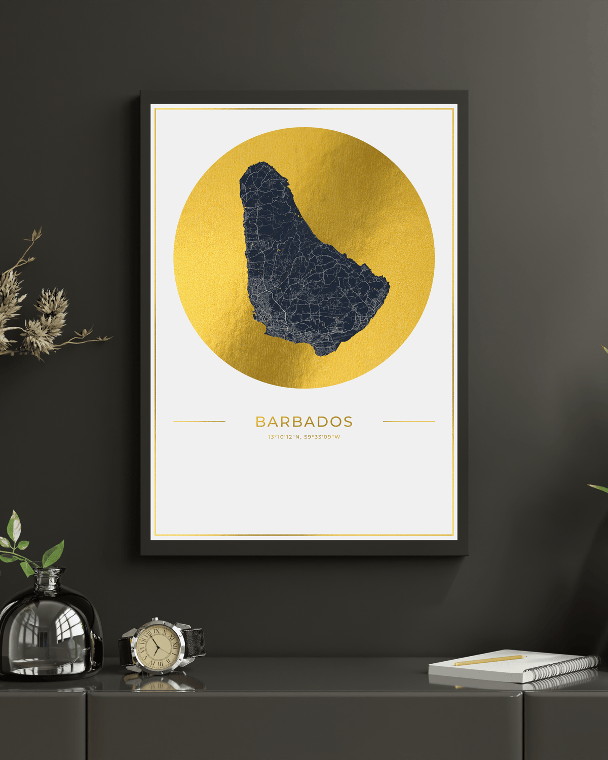 Framed Barbados map wall art hanging on a dark gray wall above a console table. The print features a navy blue map silhouette centered within a large metallic gold circle, with the word BARBADOS and smaller country text below in gold.