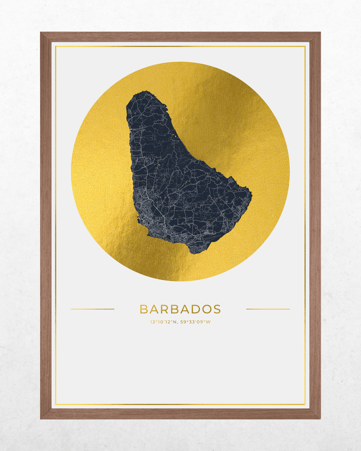 A framed art print featuring a stylized map of Barbados in dark blue set against a metallic gold circular background. The print is housed in a lbrown wood frame and displayed on a textured off-white wall.