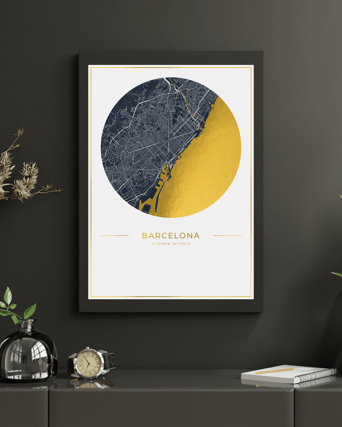 A framed minimalist map art print of Barcelona, featuring a circular design with a dark navy street map and a large mustard yellow section, displayed on a dark gray wall above a console table with decorative items.
