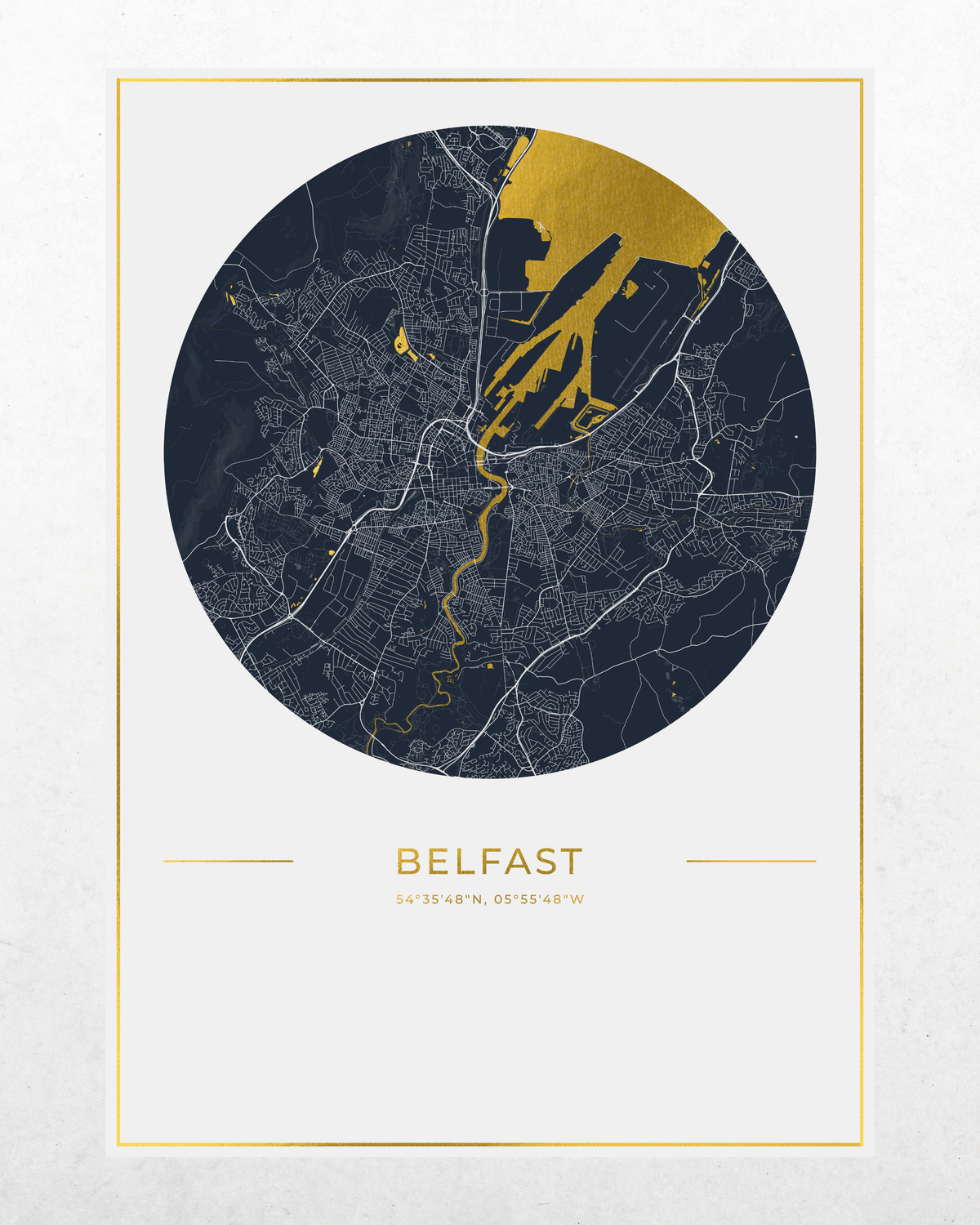 A minimalist city map print of Belfast, featuring a circular dark navy map with white street lines and gold highlights, framed by a thin gold border on a light textured background.