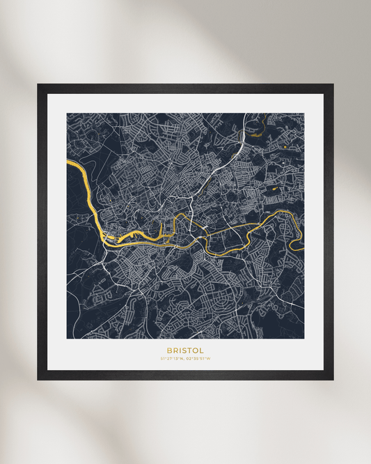 Framed city map print of Bristol, UK, featuring a dark navy street grid with white lines and a highlighted gold River Avon, presented in a black frame with a white mat.