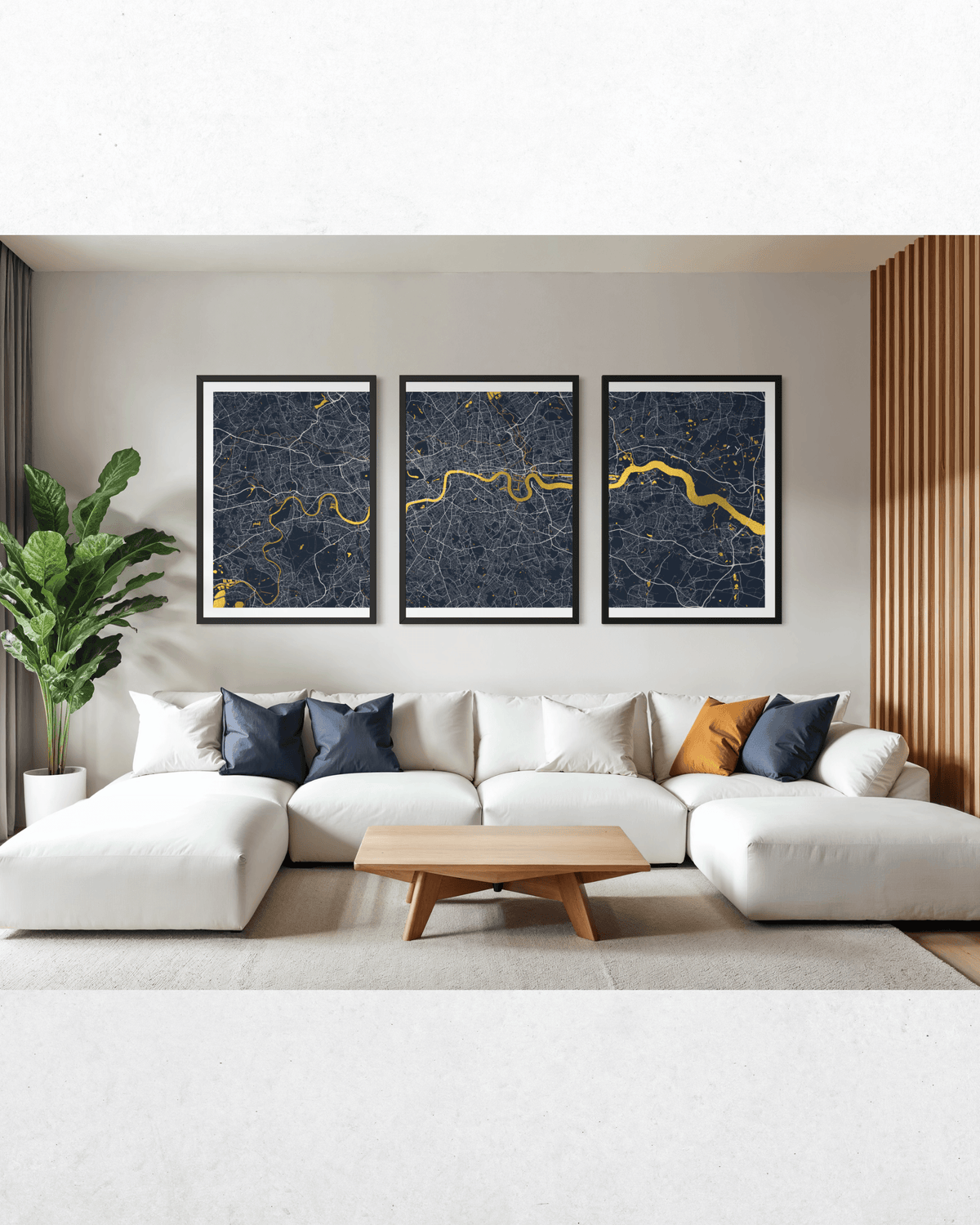 A modern living room setting featuring a three-piece framed wall art set depicting a dark blue and gold city map, hung above a white sectional sofa with navy and orange accent pillows.