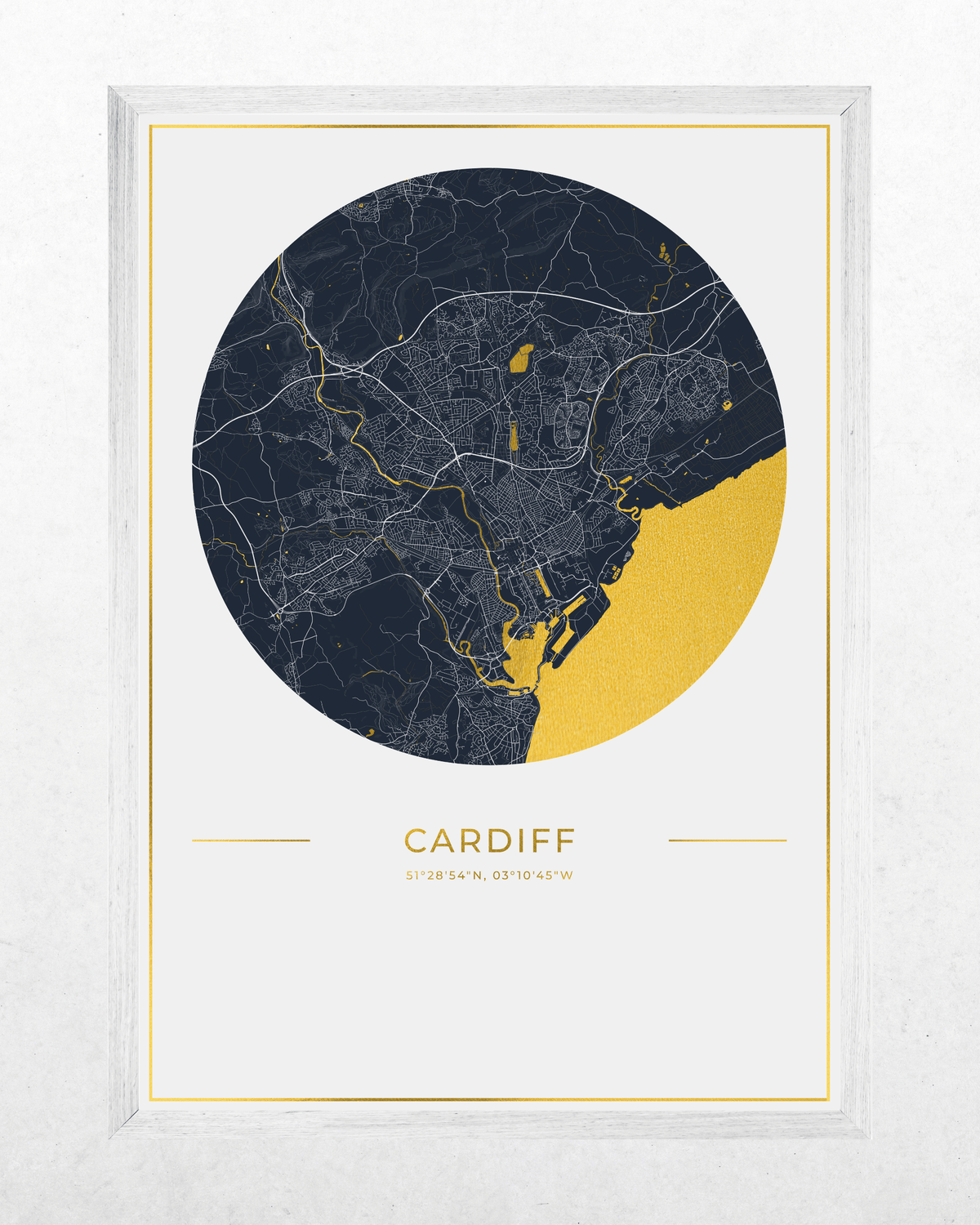 A framed minimalist city map print of Cardiff, Wales, featuring a dark navy blue circular map with fine white street lines, a large gold-colored coastal area, and the city name 'CARDIFF' printed below in gold on a white background.
