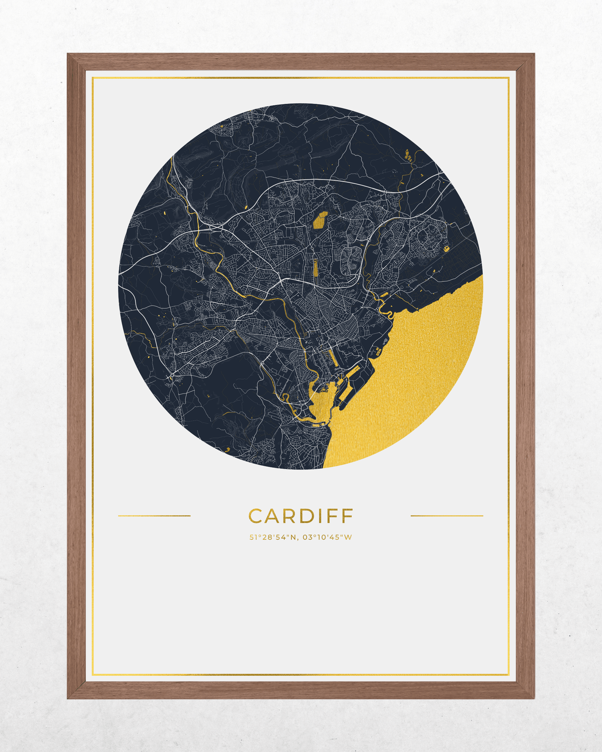 A framed city map print of Cardiff, Wales, featuring a dark navy circular map with fine white street lines and a gold foil highlights, set in a light wood frame on a white background.