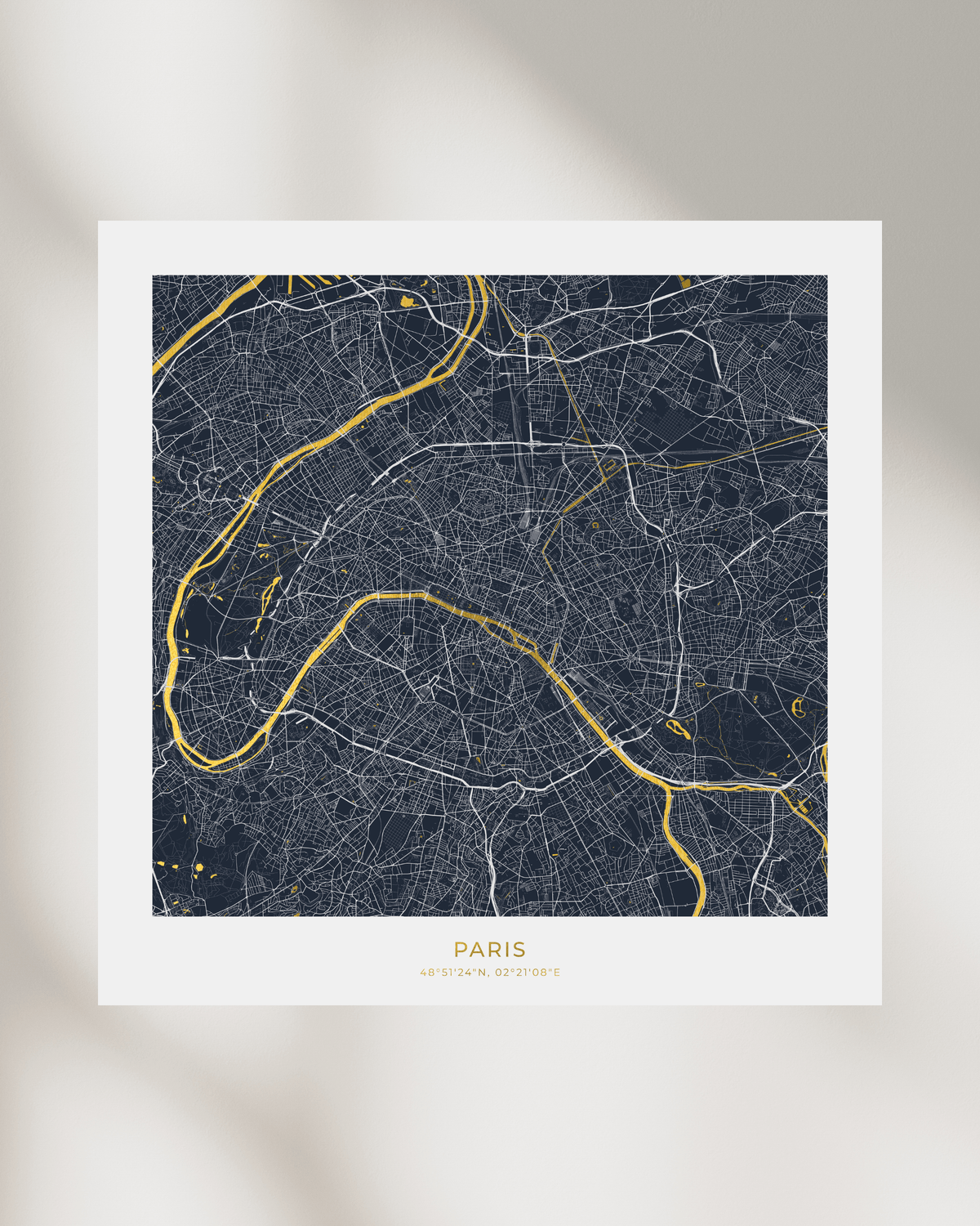 A minimalist Paris city map art print featuring a dark navy blue background with white street lines and bright gold river and text accents, displayed on a light gray background with soft shadows.