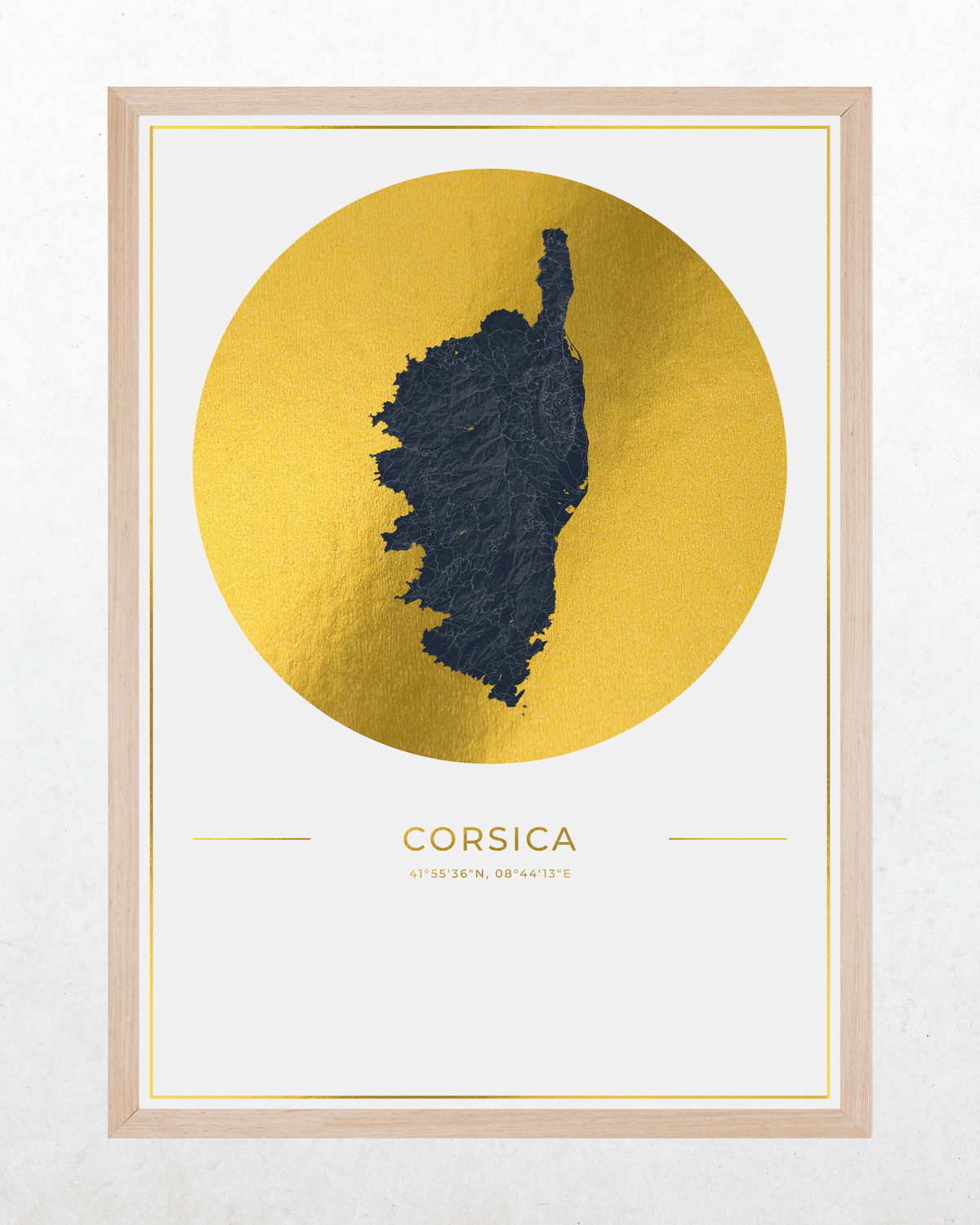 A framed art print featuring a textured dark blue map silhouette of Corsica centered within a large metallic gold circle, with the word 'CORSICA' and smaller text below, shown in a light wood frame against a white wall.