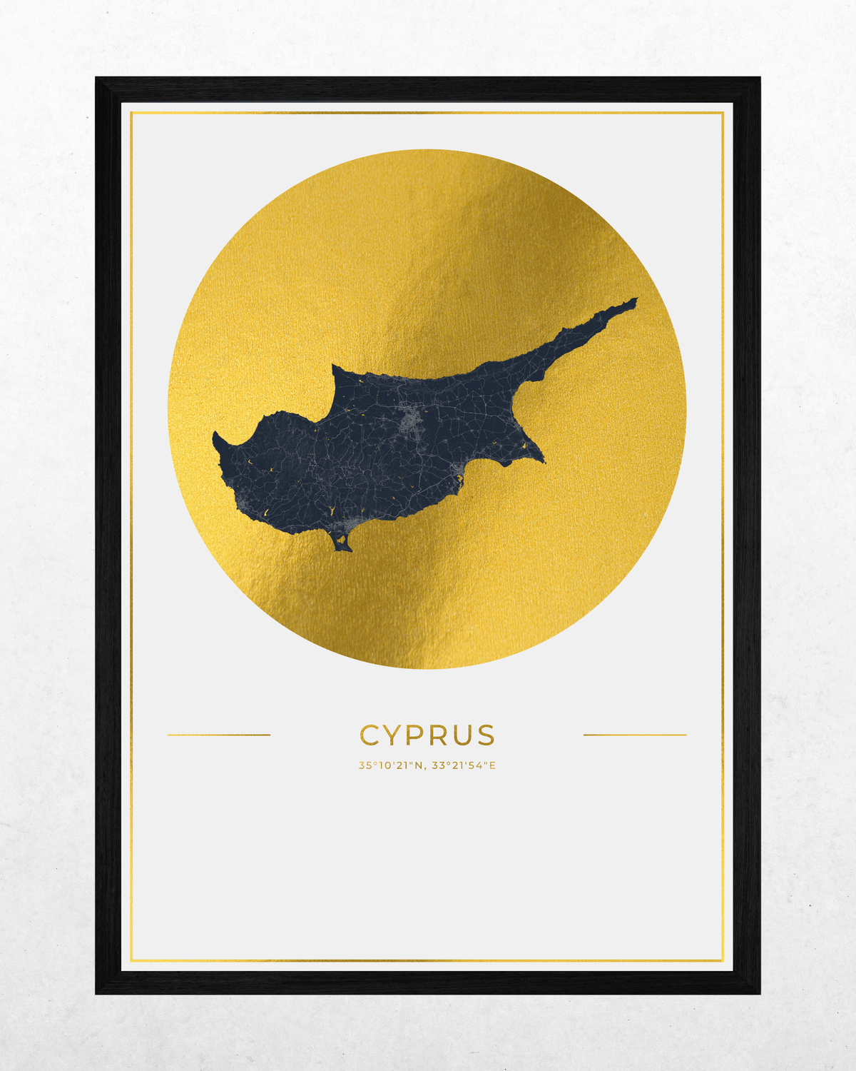 A framed minimalist art print of Cyprus, featuring a dark navy blue map silhouette inside a large textured gold circle, with the word 'CYPRUS' and coordinates below, set in a black frame against a light gray wall.
