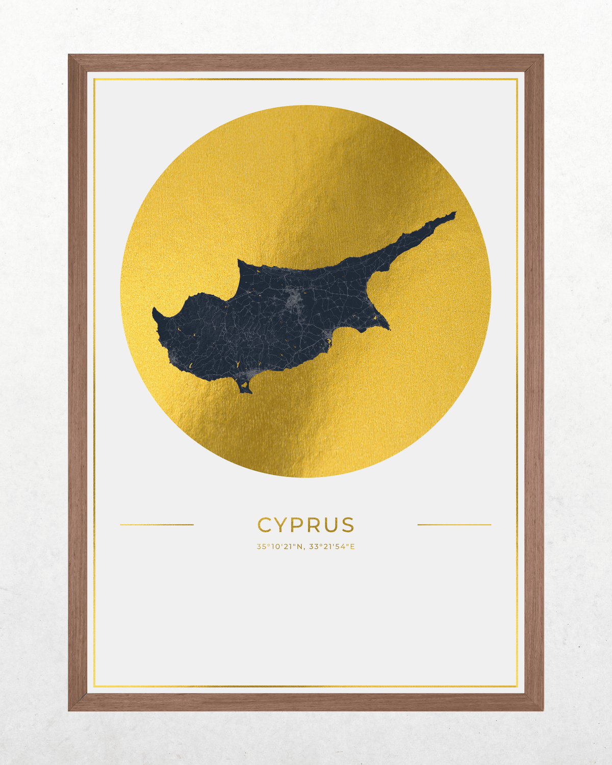 Framed wall art featuring a dark navy silhouette map of Cyprus over a large textured gold circle, with the word "CYPRUS" and coordinates below, shown in a brown wood frame on a light wall.