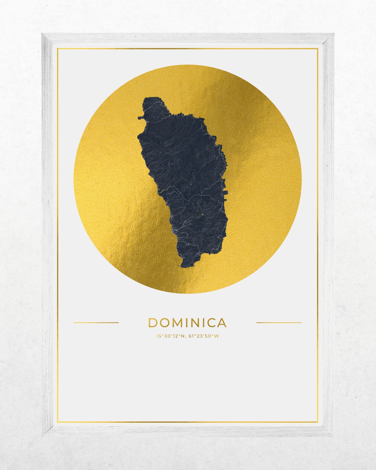 A framed minimalist art print of the Dominican Republic map, featuring a textured dark gray island silhouette centered inside a metallic gold circle on a white background, with 'DOMINICA' and coordinates printed below. The print is housed in a light gray frame against a textured white wall.