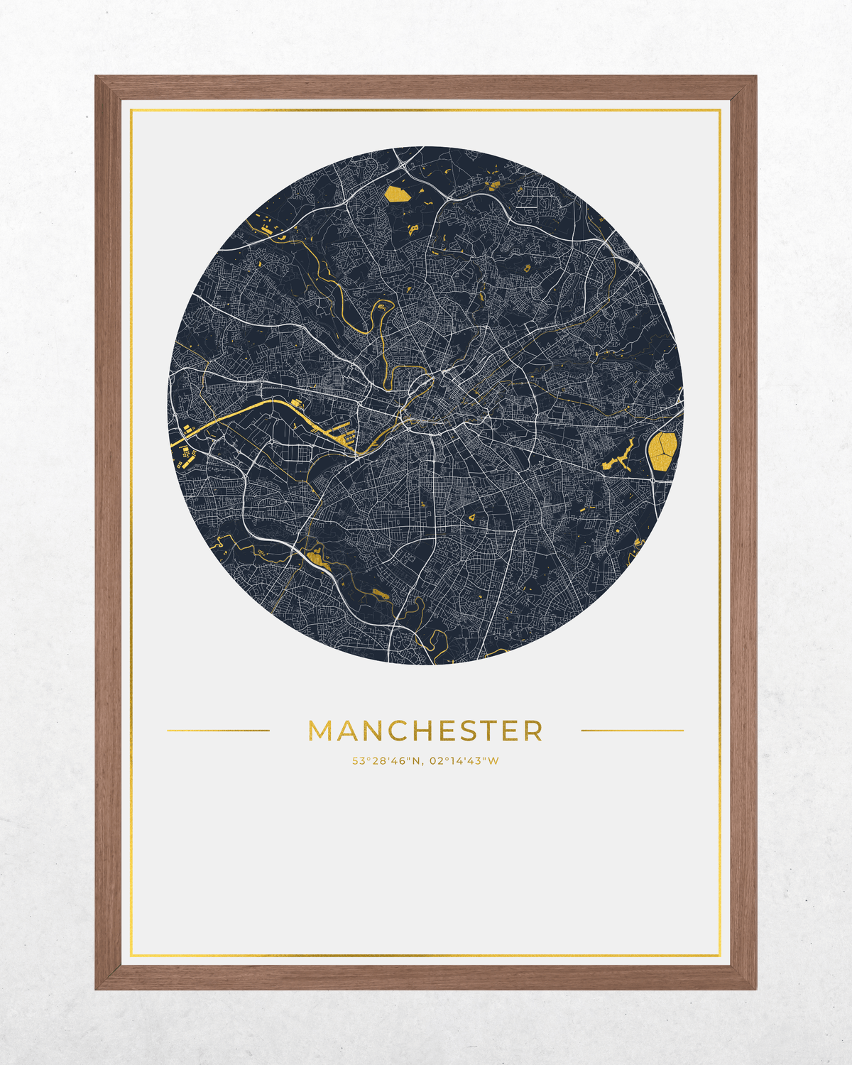 A framed circular city map print of Manchester, featuring a dark navy street network with gold highlights on an off-white background, surrounded by a brown wood frame.