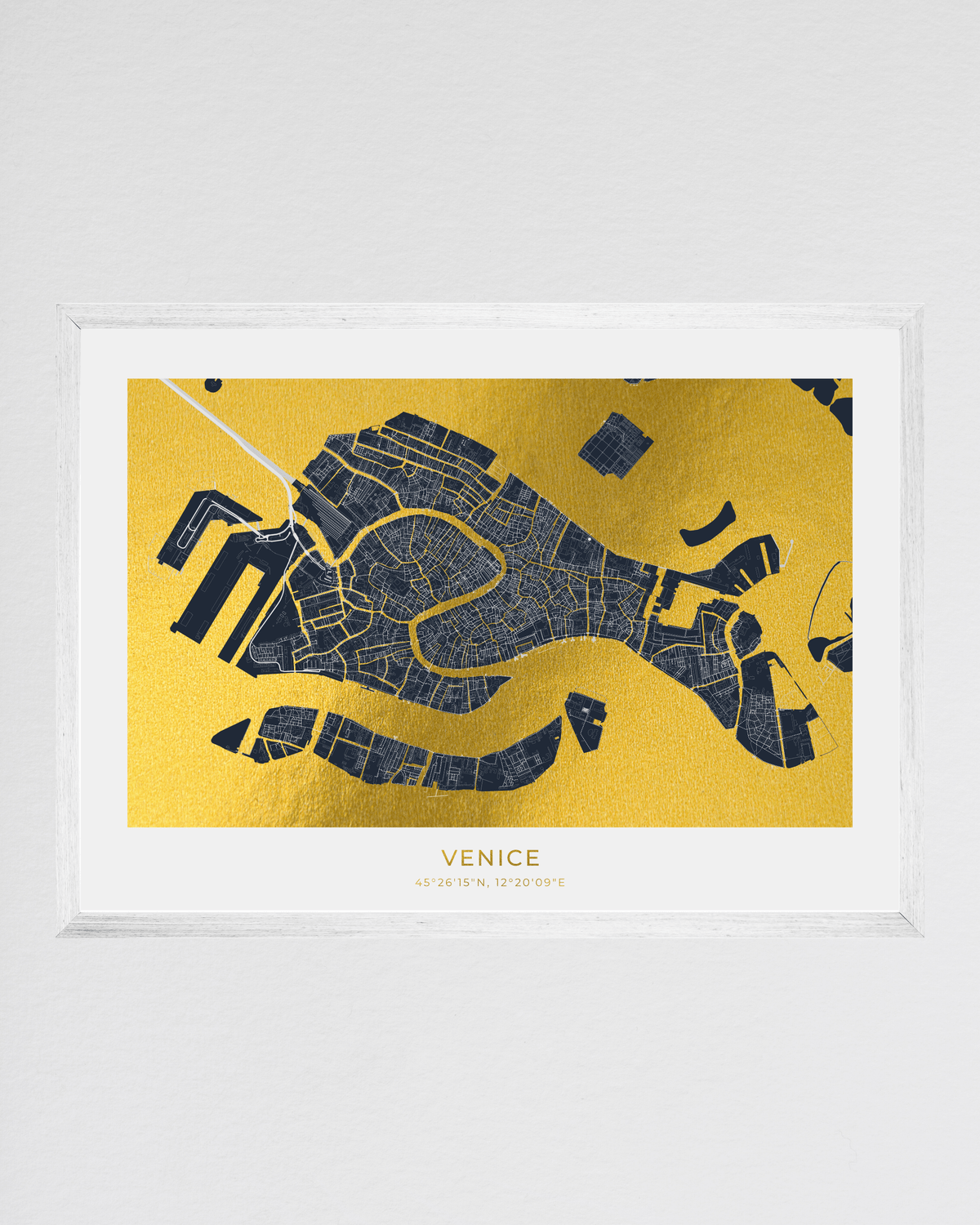 A framed map print of Venice featuring a dark navy street layout on a textured gold background, presented in a clear acrylic frame against a light gray wall.