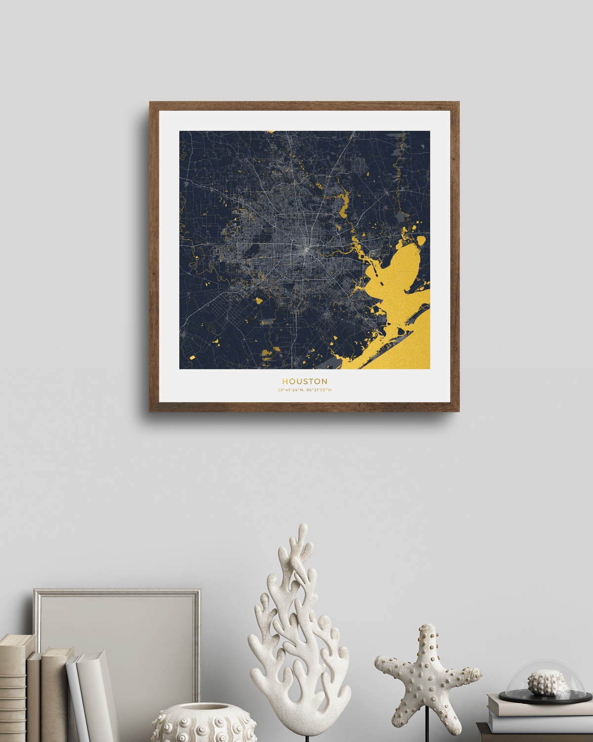 A framed Houston city map art print with a dark navy background, bright gold highlighted areas, and a white mat, hanging on a light gray wall above decorative home decor objects.