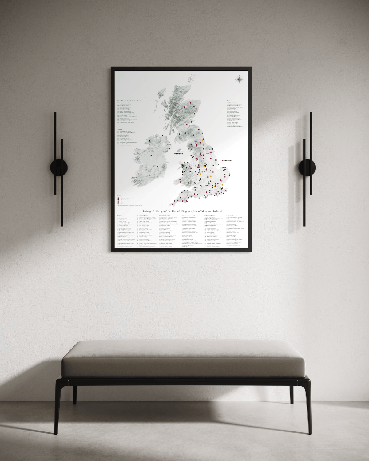 A framed map poster of the United Kingdom AND IRELAND hangs on a light gray wall above a minimalist bench, flanked by two black wall sconces.