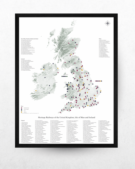 A framed poster print of a historical railway map of the United Kingdom, Ireland, and Britain, featuring numerous colored dots marking heritage railway stations. The poster is housed in a black frame and displayed against a light gray textured wall.