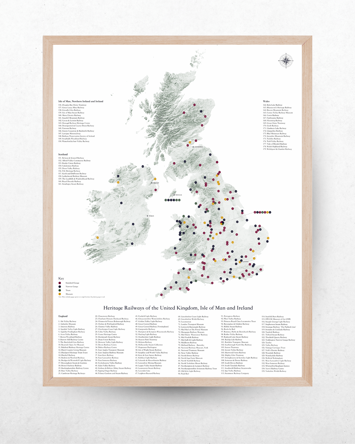 A framed vintage-style map poster of the United Kingdom and Ireland, featuring a light wood frame, a detailed gray and white map with numerous colored railway station markers, and extensive station lists printed along the bottom.