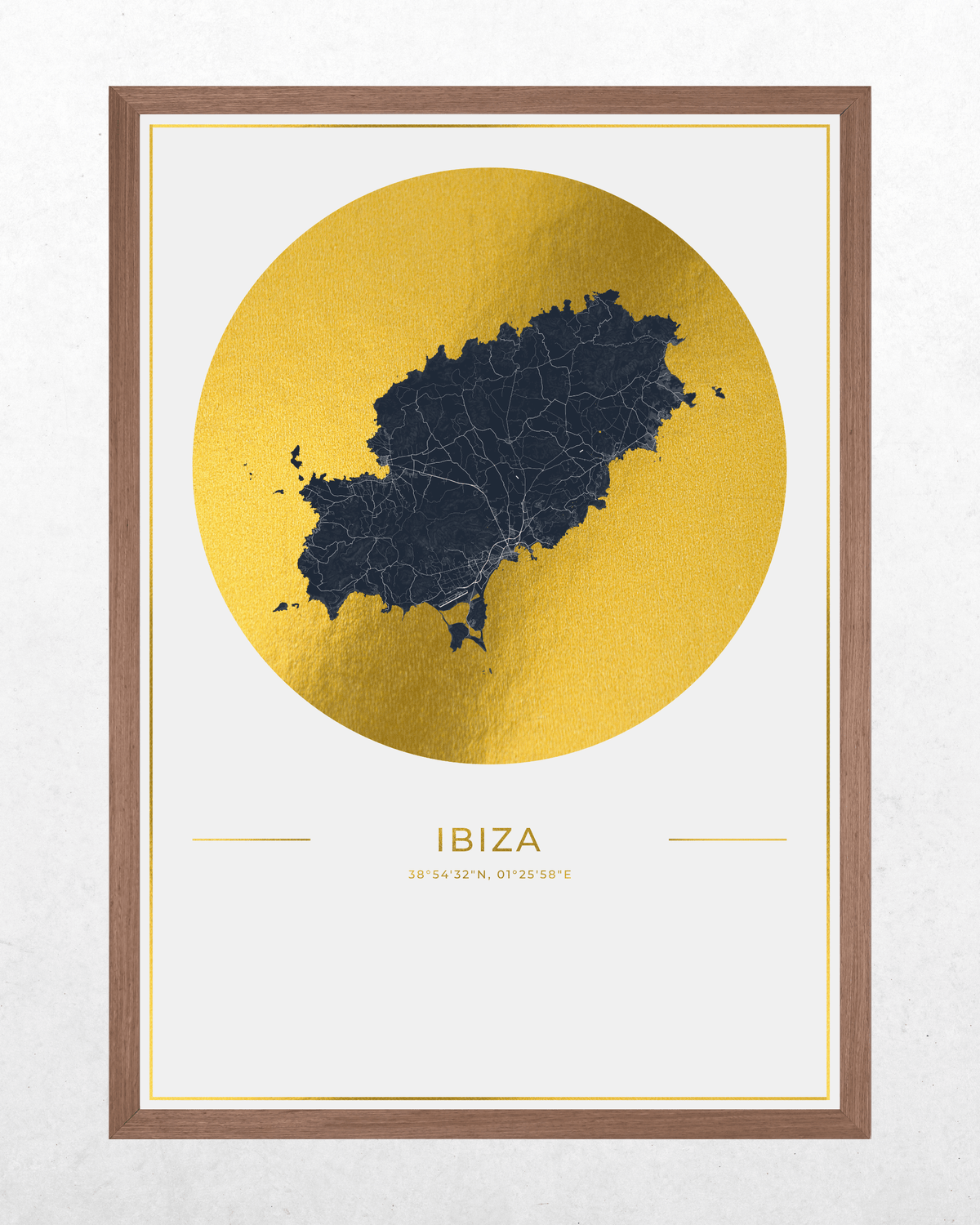 Framed wall art print featuring a dark navy map of Ibiza inside a large metallic gold circle, with the word 'IBIZA' and coordinates printed below, shown in a brown wood frame against a light textured wall.
