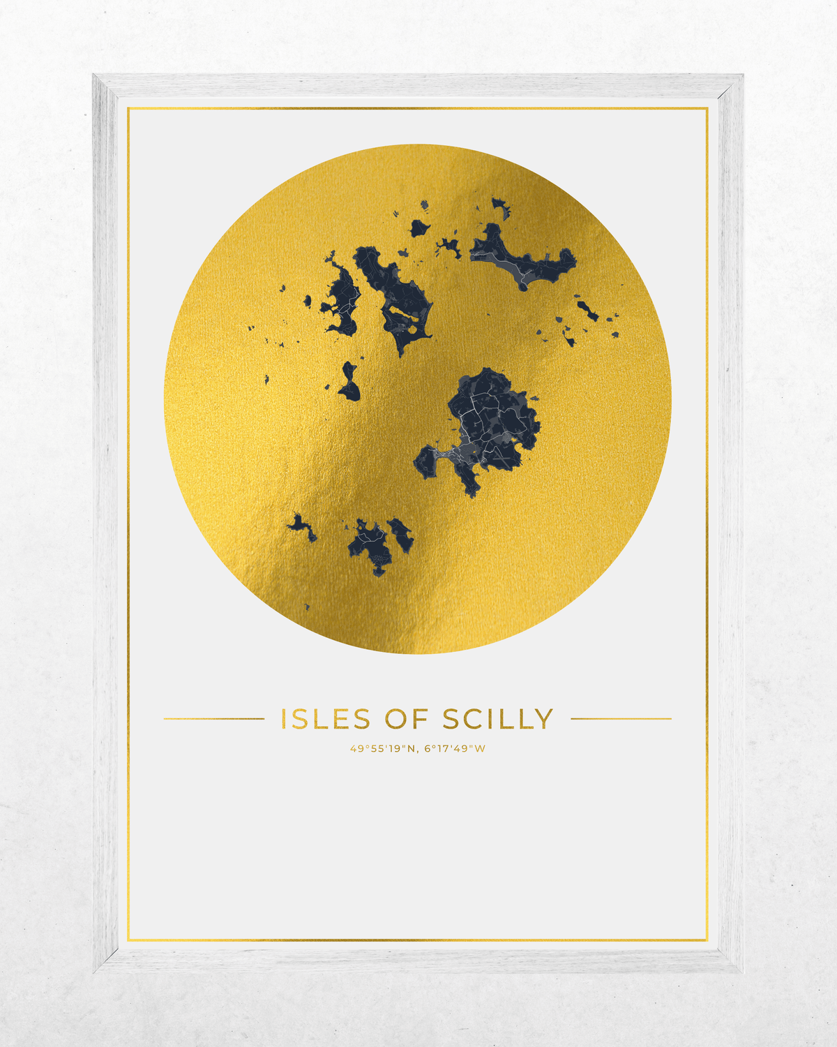 Framed wall art print featuring a large metallic gold circle with a dark blue map of the Isles of Scilly and the text 'ISLES OF SCILLY' below, shown in a white frame against a light textured wall.