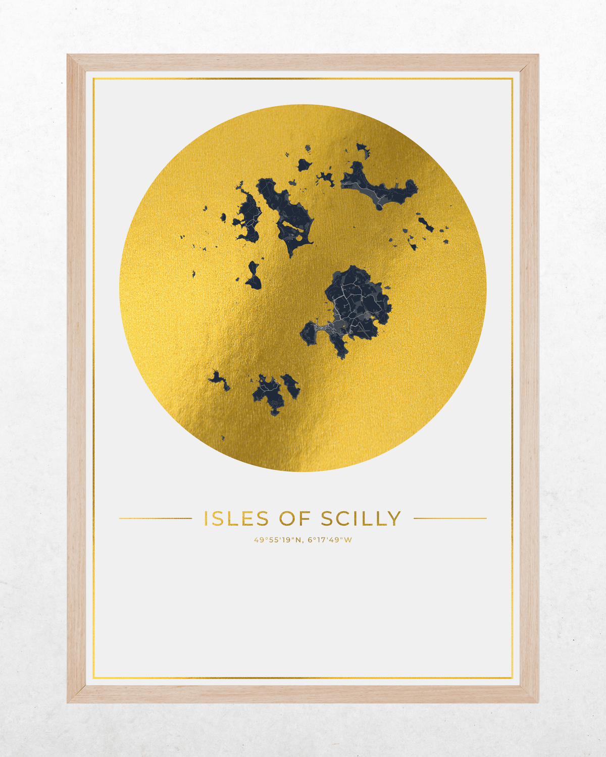 Framed wall art print featuring a large metallic gold circle with a dark blue map of the Isles of Scilly and the text 'ISLES OF SCILLY' on a white background, set in a light wood frame.