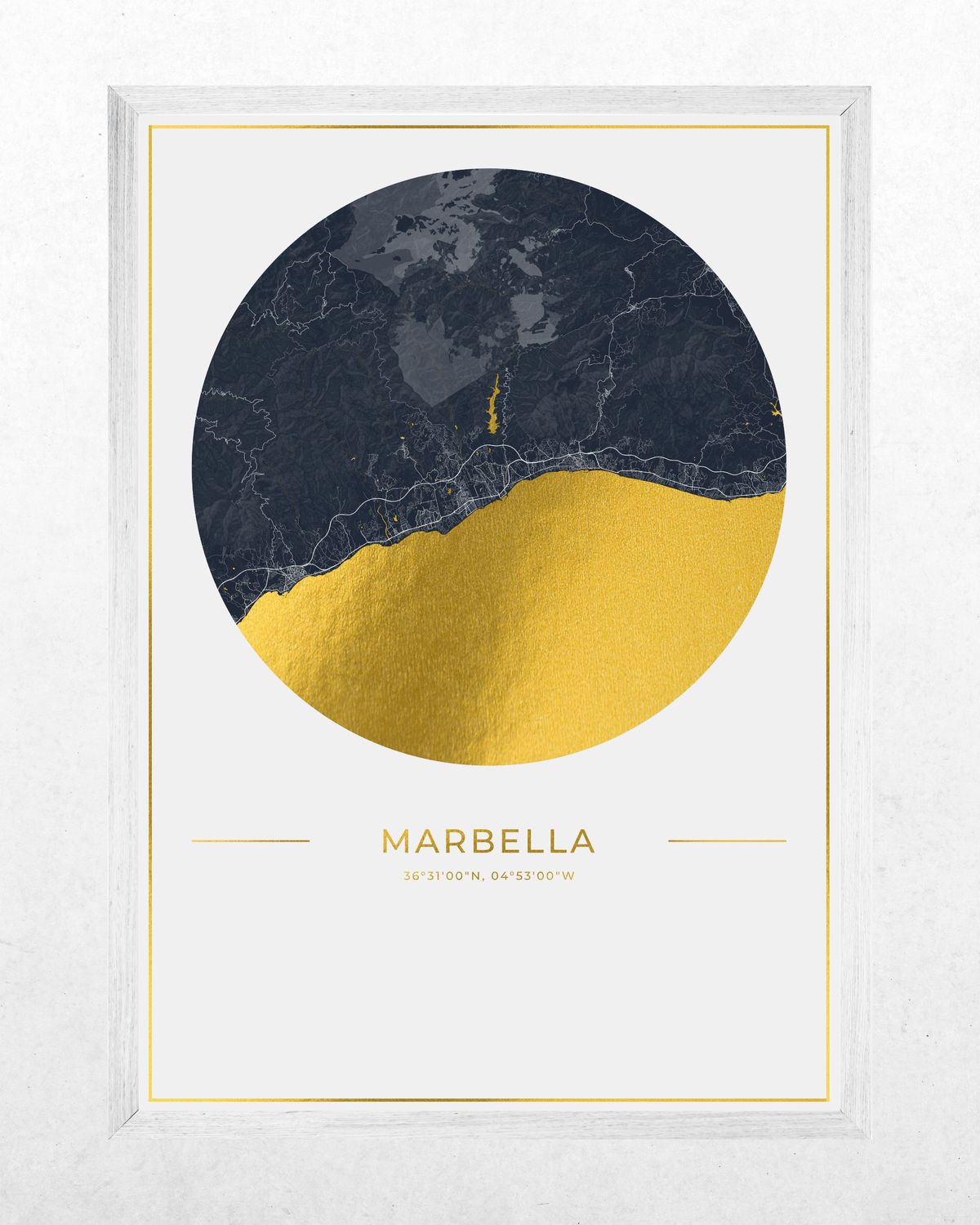 A framed minimalist art print featuring a circular design split into dark navy and metallic gold foil textures, with the word 'MARBELLA' and coordinates printed below, set against a light textured background.