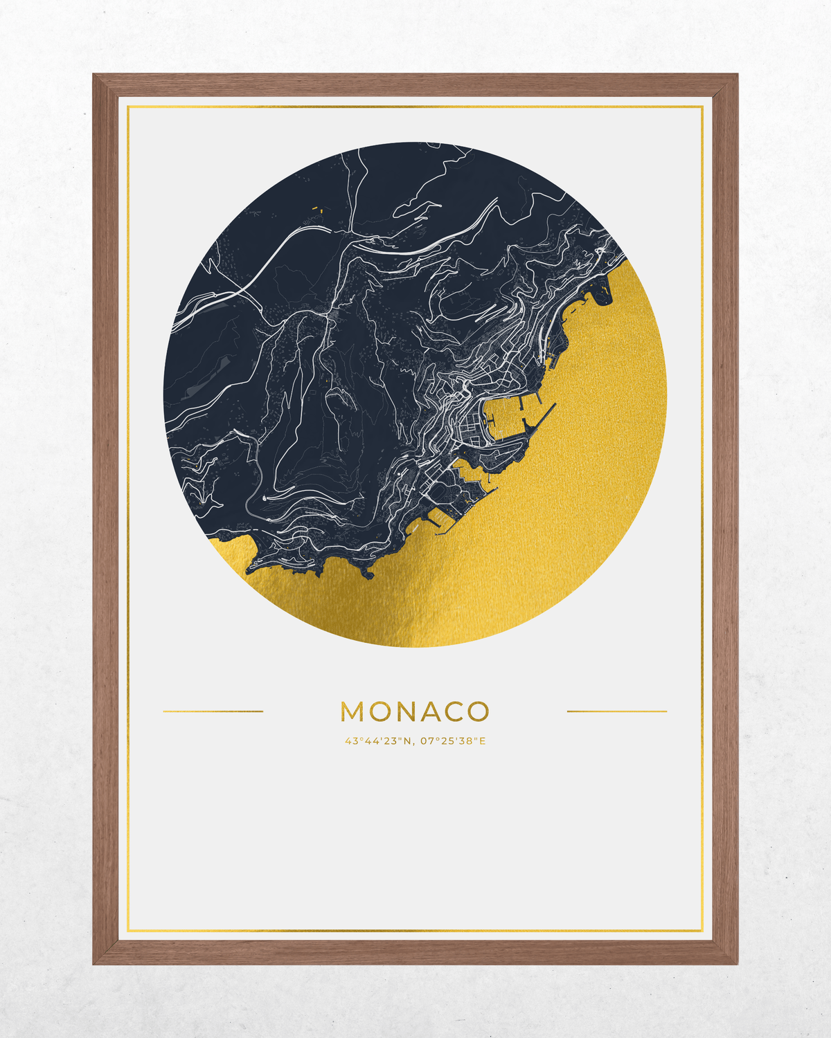 Framed wall art print featuring a stylized circular map of Monaco in navy blue and metallic gold, with the city name printed below, shown against a light textured wall.