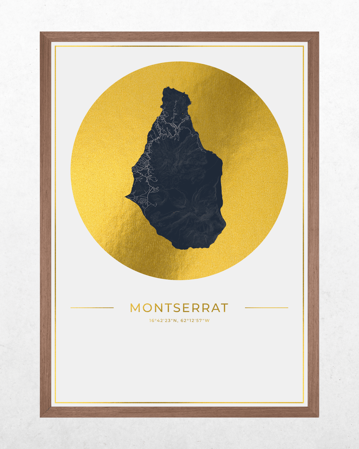 Framed wall art print featuring a dark navy silhouette map of Montserrat over a large metallic gold circle, with the word 'MONTSERRAT' and smaller text below, shown in a brown wood frame against a light textured wall.