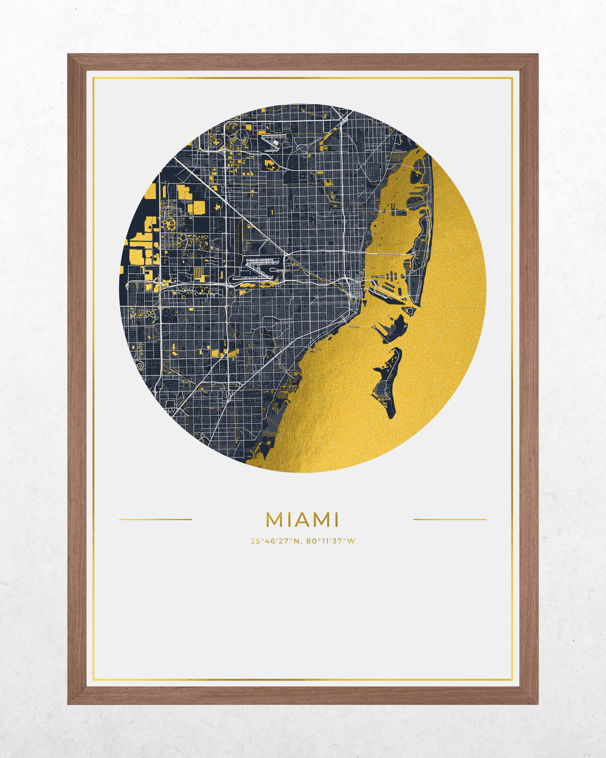 A framed minimalist map print of Miami, Florida, featuring a circular street map in dark navy and gold over a white background, with the city name 'MIAMI' and coordinates printed below. The print is housed in a light brown wood frame.