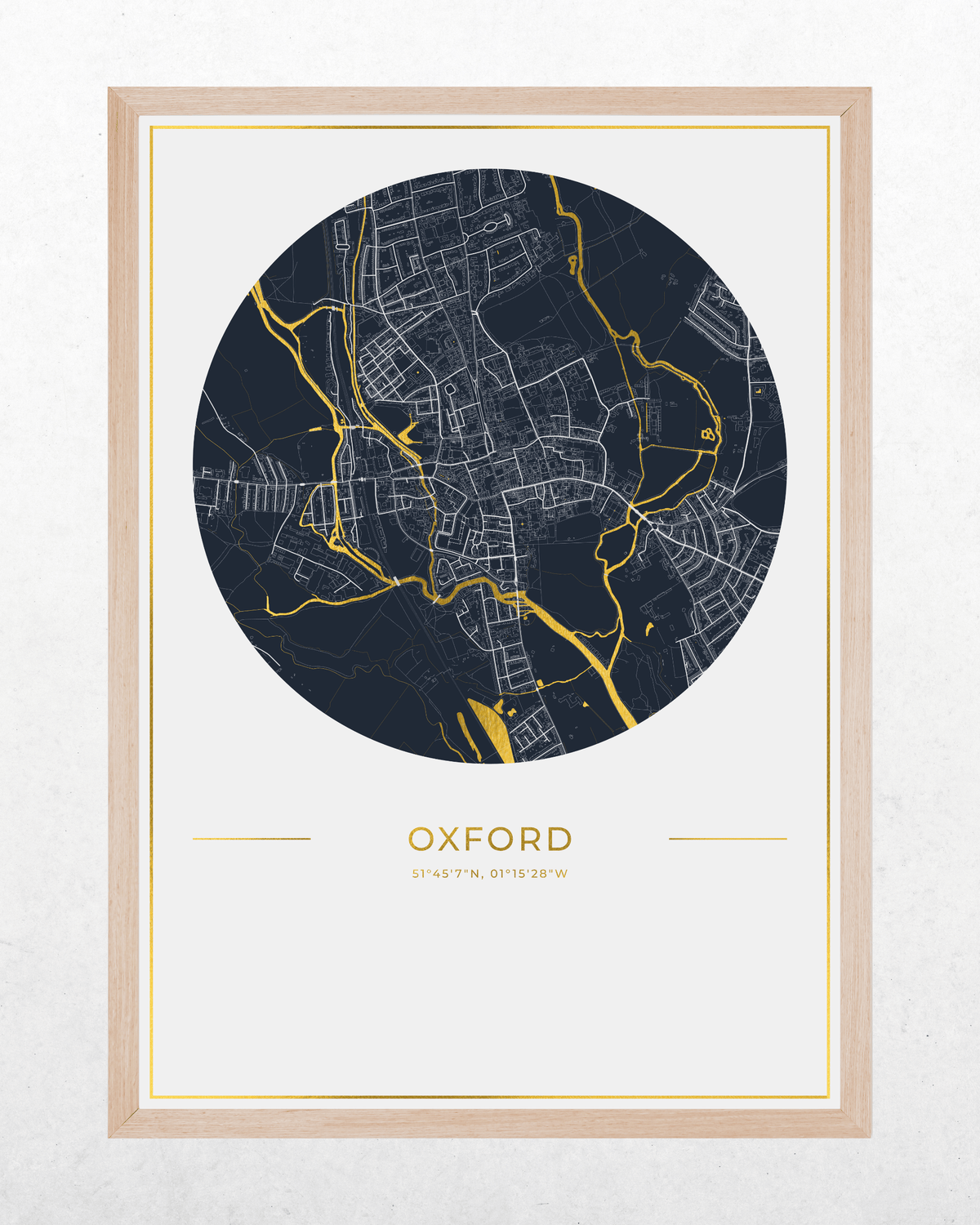 A framed circular map print of Oxford, London, featuring a dark navy blue map with gold river highlights on a white background, enclosed in a light wood frame.