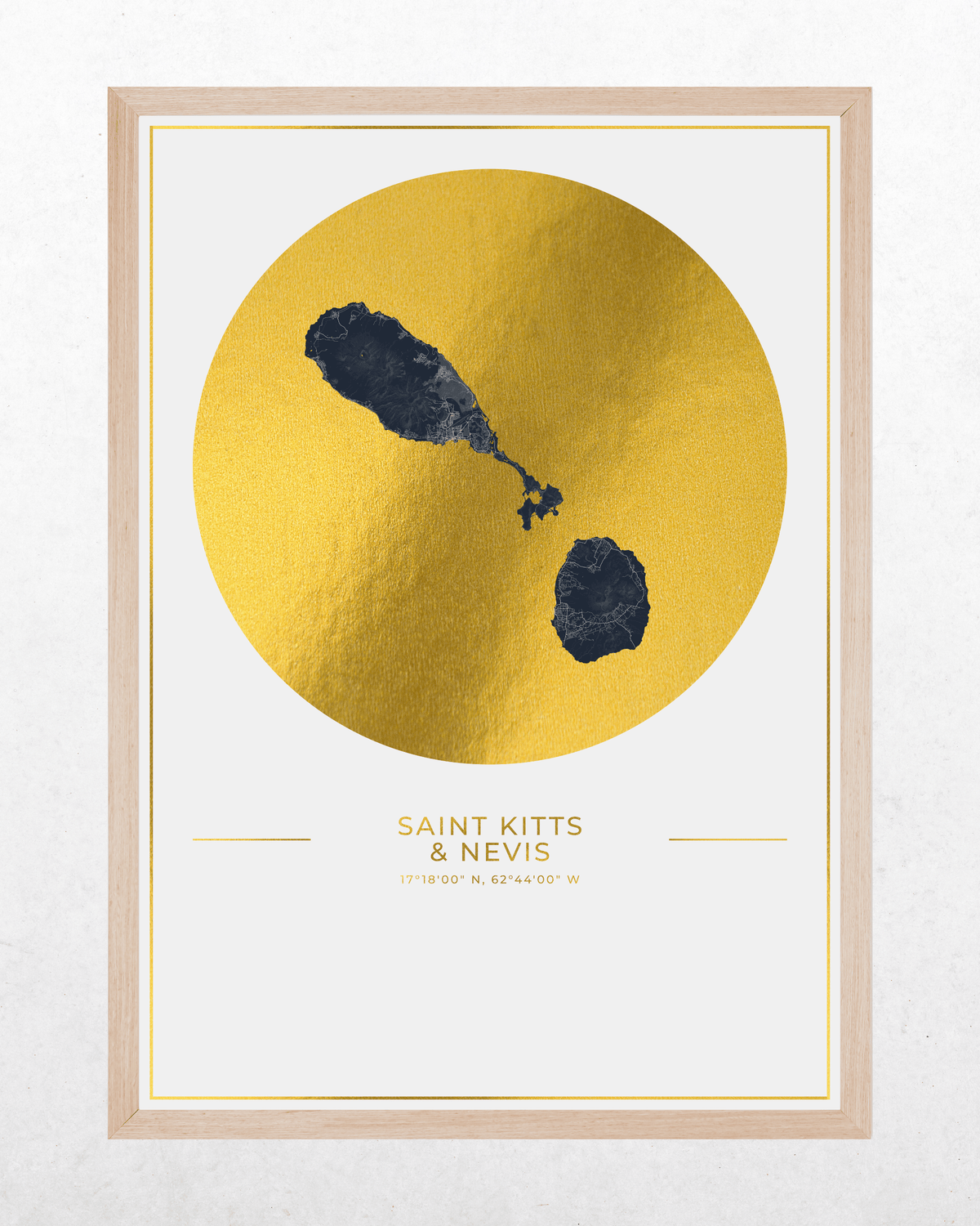 A framed minimalist art print featuring a textured gold circle with a map of Saint Kitts & Nevis on a white background, with the text 'SAINT-KITTS & NEVIS' and coordinates printed below. The print is framed in a light natural wood frame.