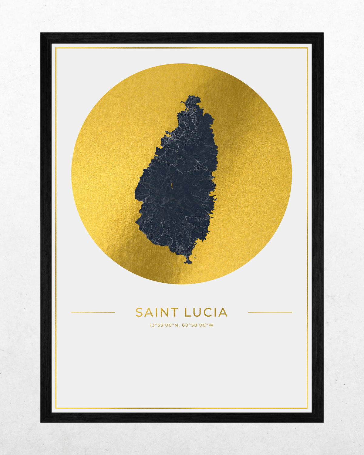 A framed minimalist map print of Saint Lucia, featuring a dark blue island silhouette centered within a large textured gold circle on a white background, with the text 'SAINT LUCIA' and coordinates below. The print is enclosed in a thin white mat and a black frame, shown against a light gray wall.