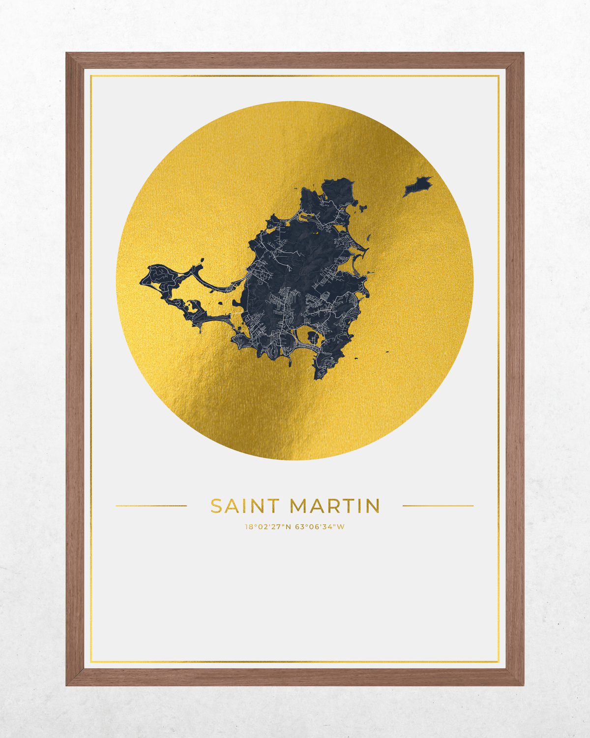 Framed wall art print featuring a stylized dark blue map of Saint Martin inside a large metallic gold circle, with the text 'SAINT MARTIN' and coordinates below, shown in a brown wood frame against a light textured wall.