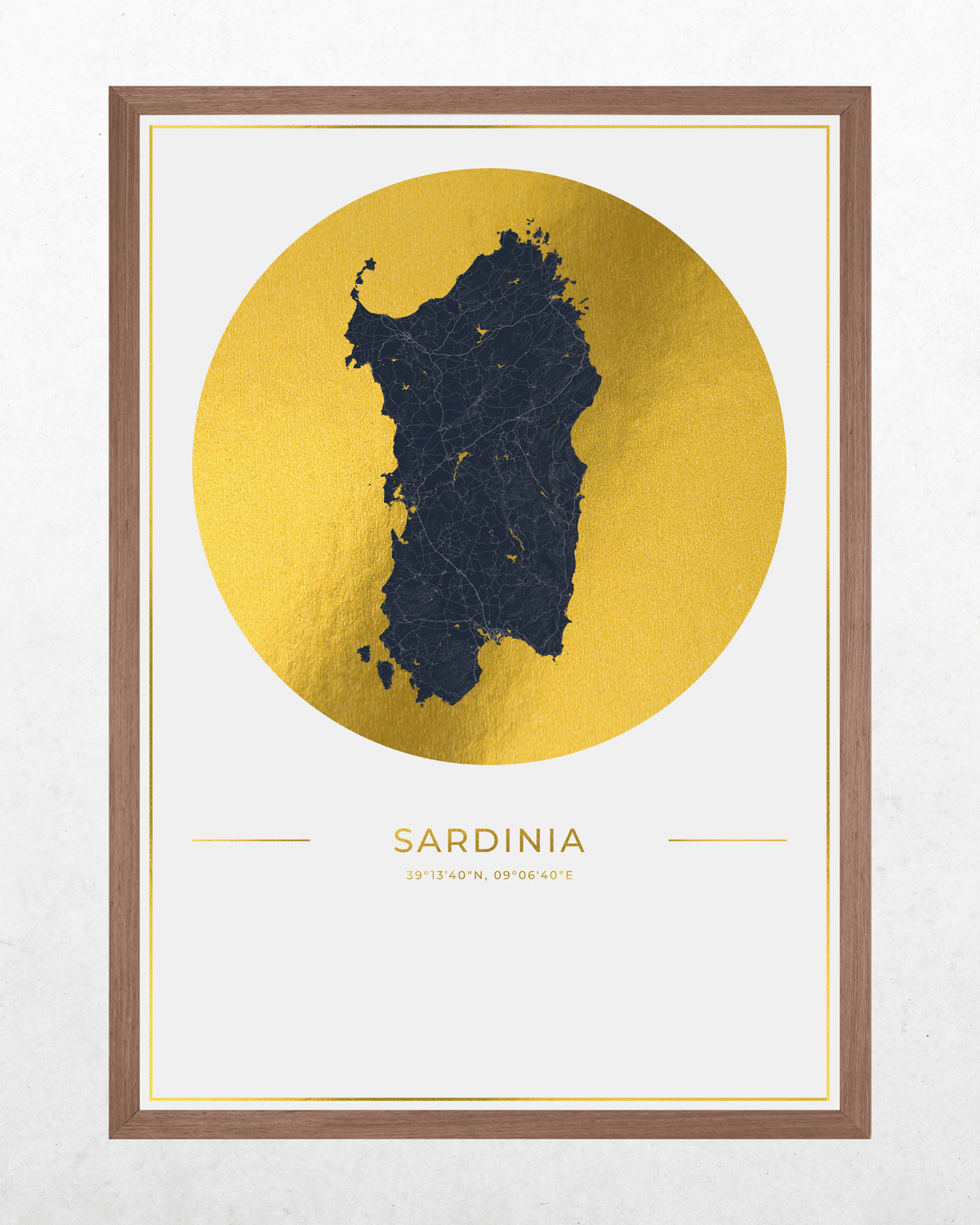 Framed wall art featuring a dark navy map silhouette of Sardinia centered inside a large metallic gold circle on a white background, with the word SARDINIA and coordinates printed below. The print is housed in a medium brown wood frame and shown against a light textured wall.