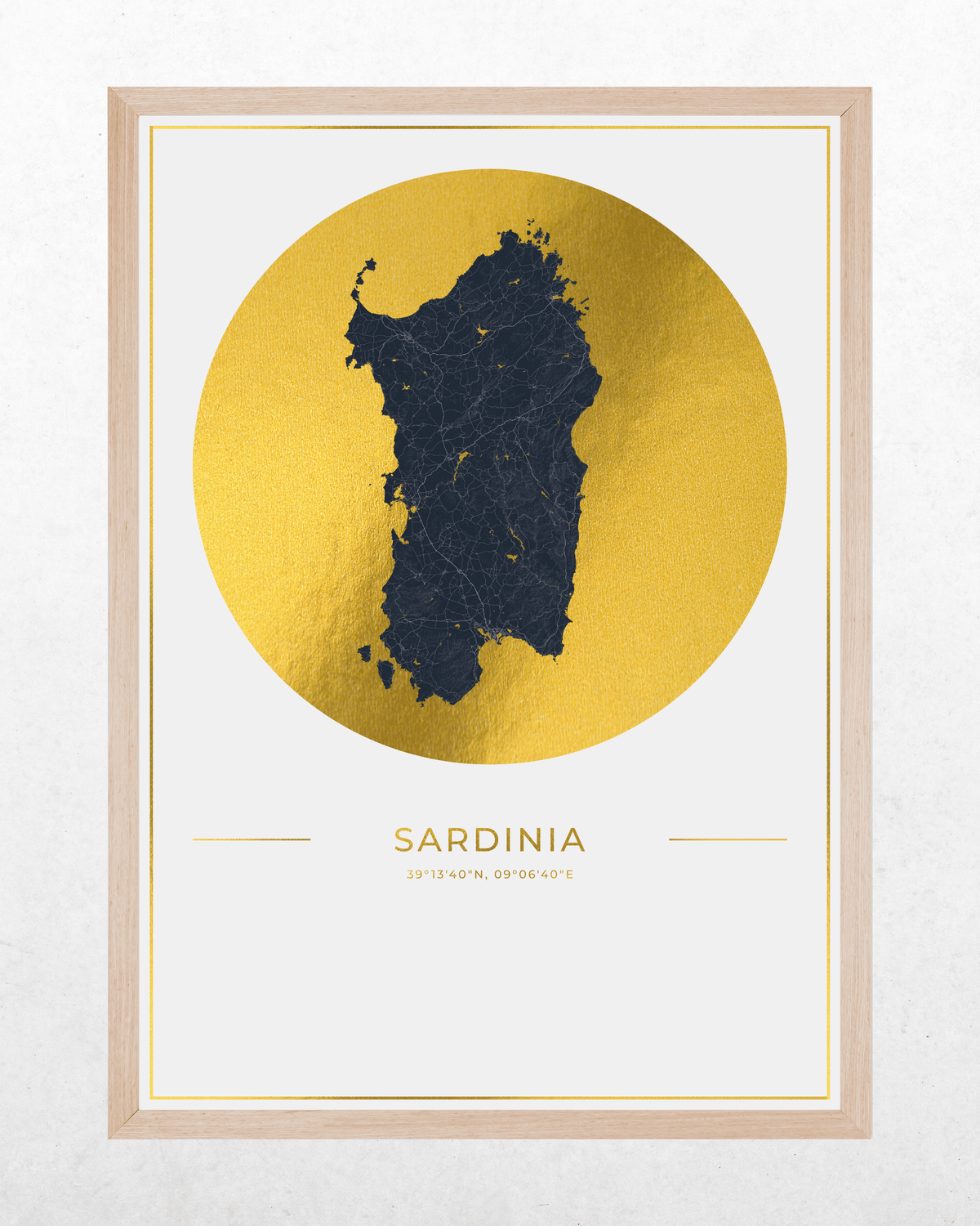 A framed minimalist art print of Sardinia, featuring a dark navy blue map silhouette of the island set against a large textured gold circle, with 'SARDINIA' printed below in gold. The print is housed in a light natural wood frame and displayed on a light gray textured wall.