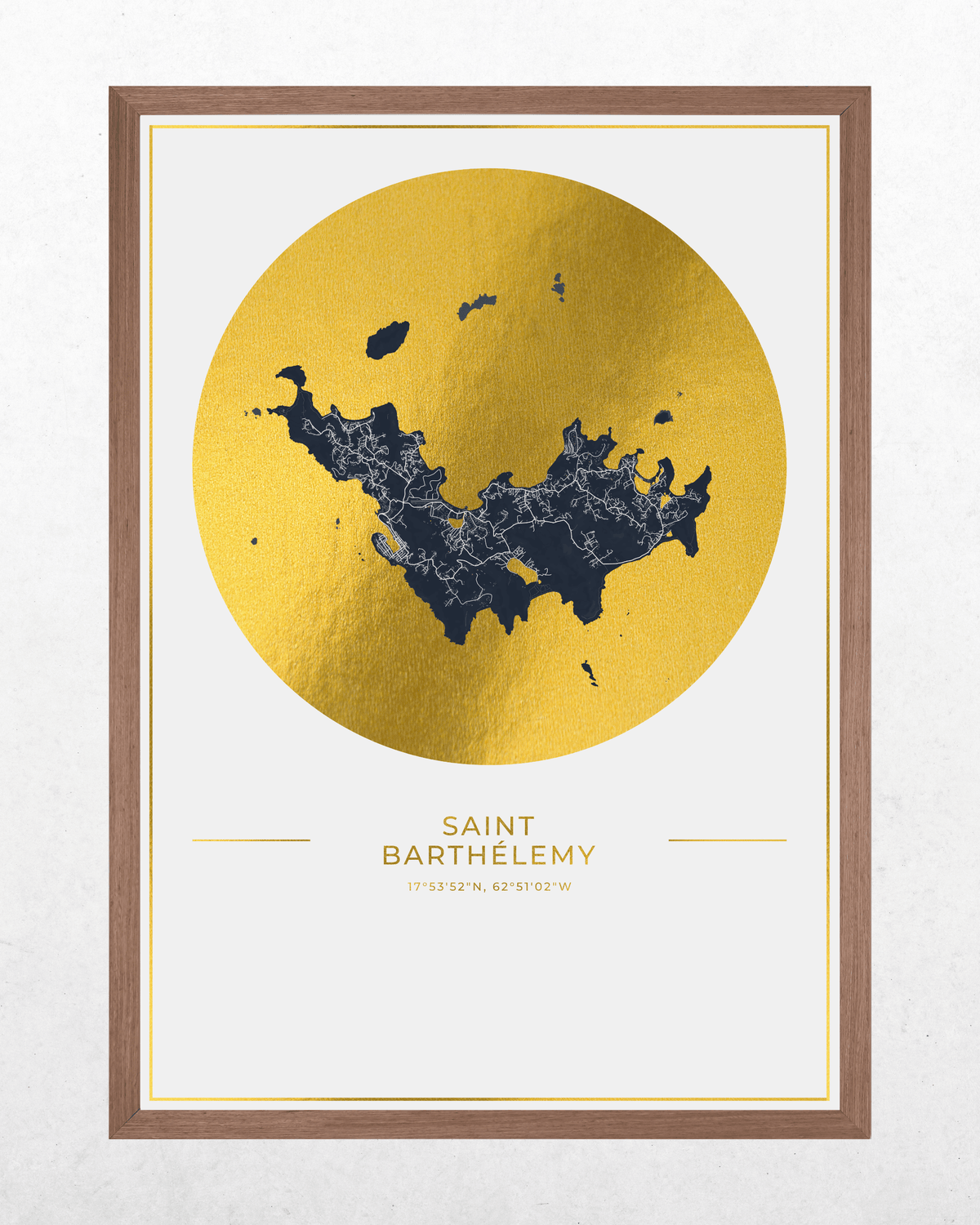 Framed wall art featuring a gold map of Saint Barthelmy centered inside a large metallic gold circle, with the city name printed below in gold. The print has a white mat and a medium brown wood frame, shown against a light textured wall.