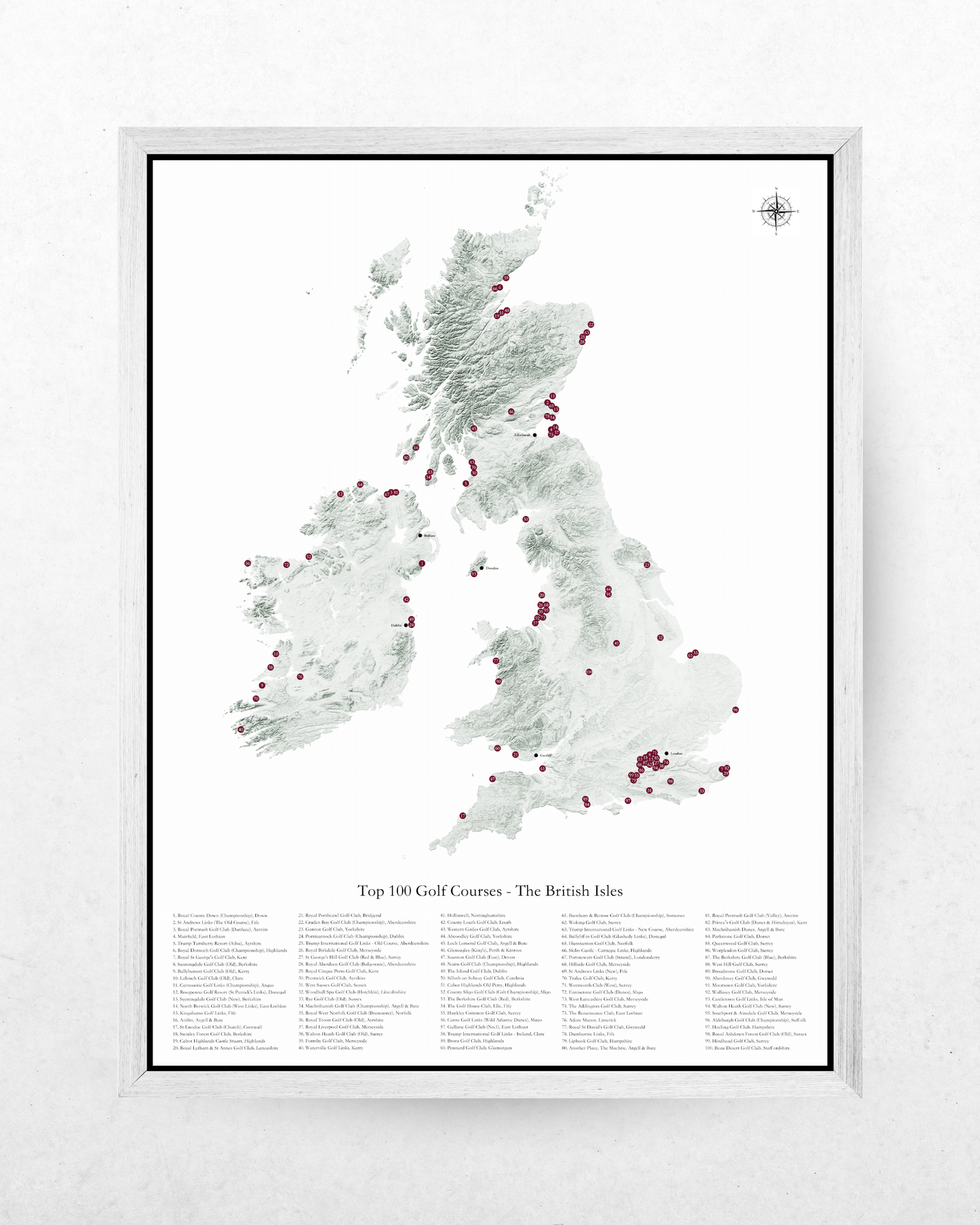 A framed map print of the British Isles showing the top 300 golf courses, with a white frame and a light textured wall background.