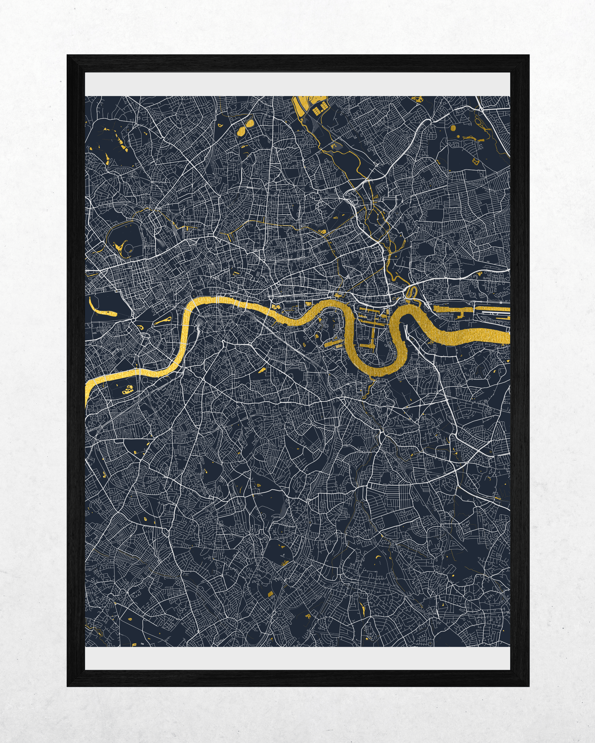 A framed city map print featuring a dark navy background with fine white street lines and a prominent golden-yellow river running horizontally through the center, shown in a black frame against a light textured wall.