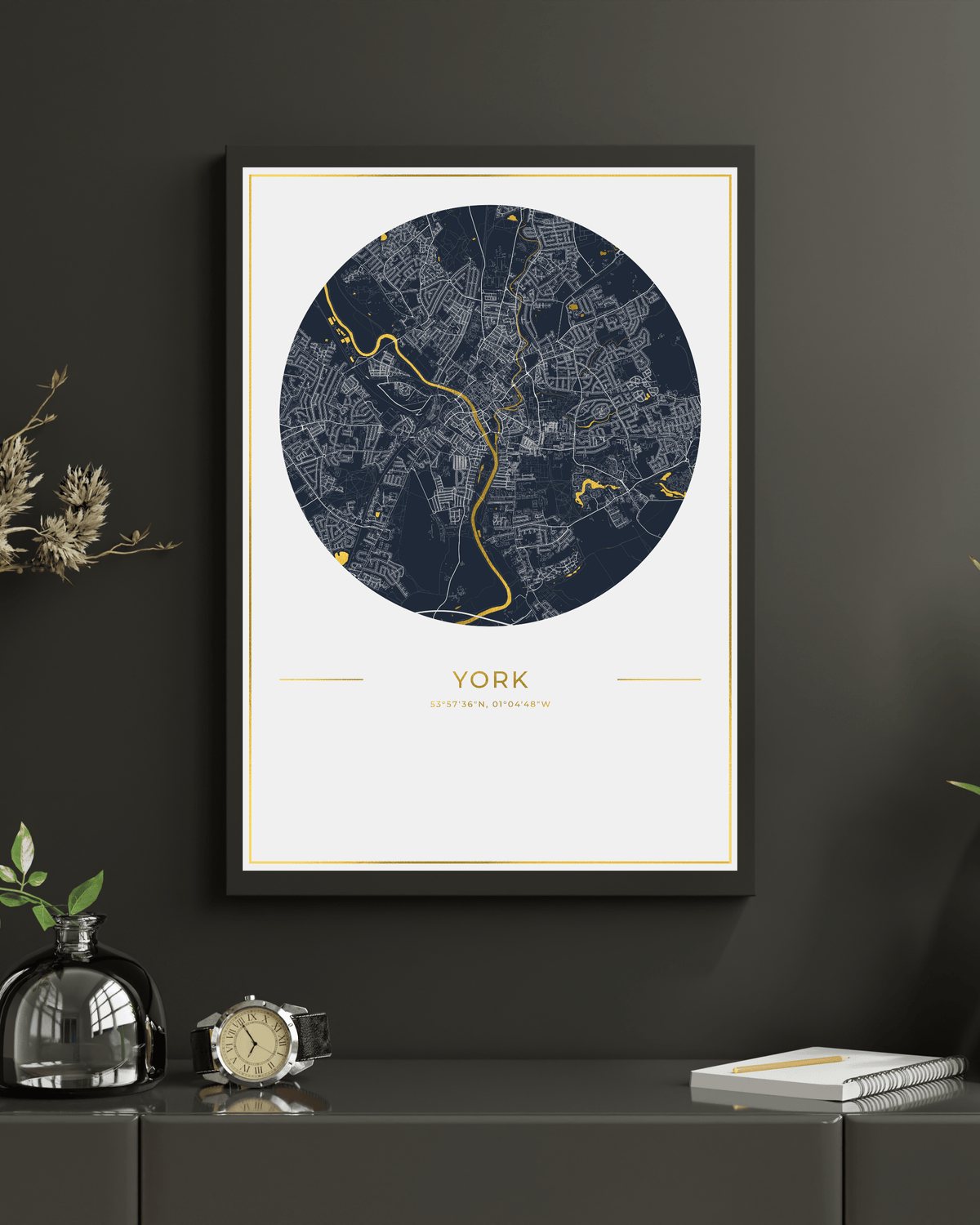 A framed circular city map print of York, England, displayed on a dark gray wall above a console table with decorative objects.